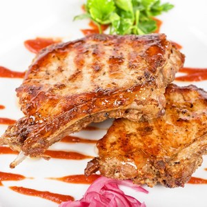 Roasted pork meat at plate with greens