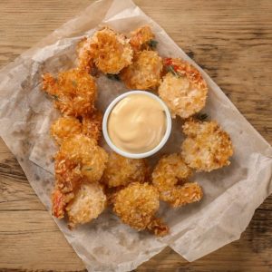 Tasty shrimp basket and sauce on wooden table